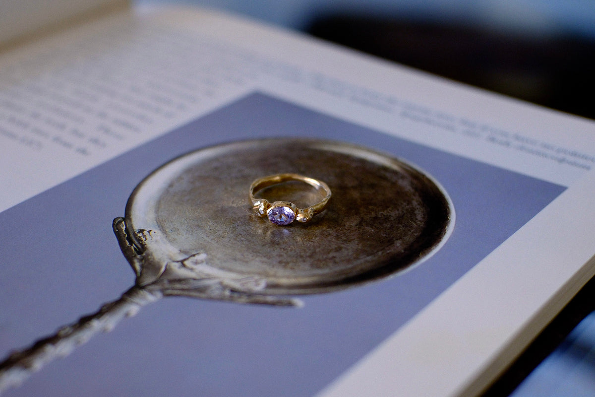 Gold ring with lavender gemstone on open book.