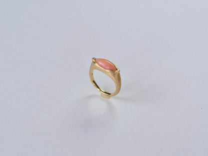 Gold ring with a  largepink stone on a light gray background