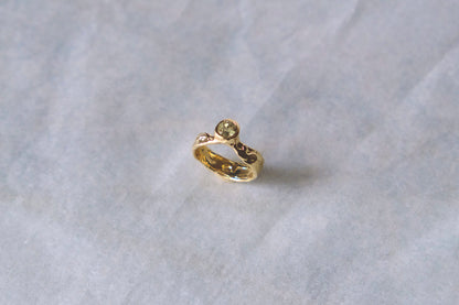 Organic gold ring with green gemstone on white background.