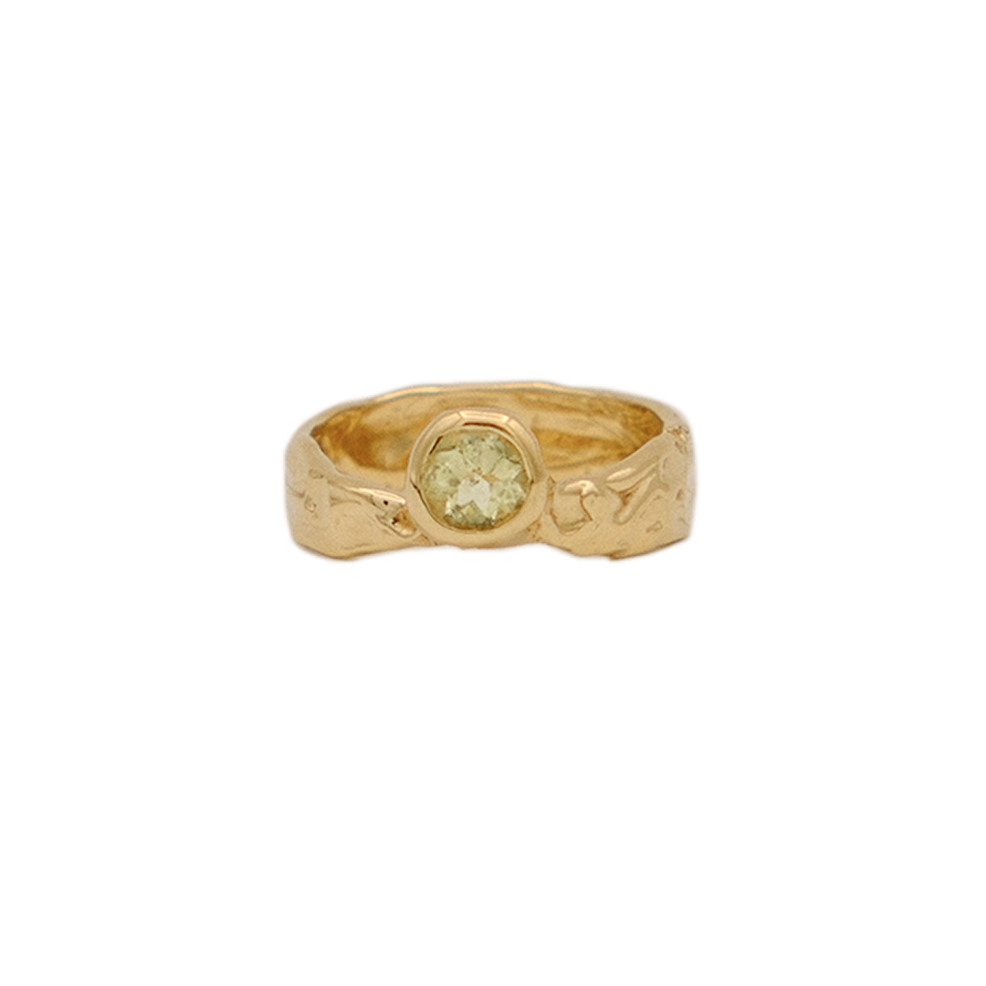 Gold ring with a green gemstone on a white background