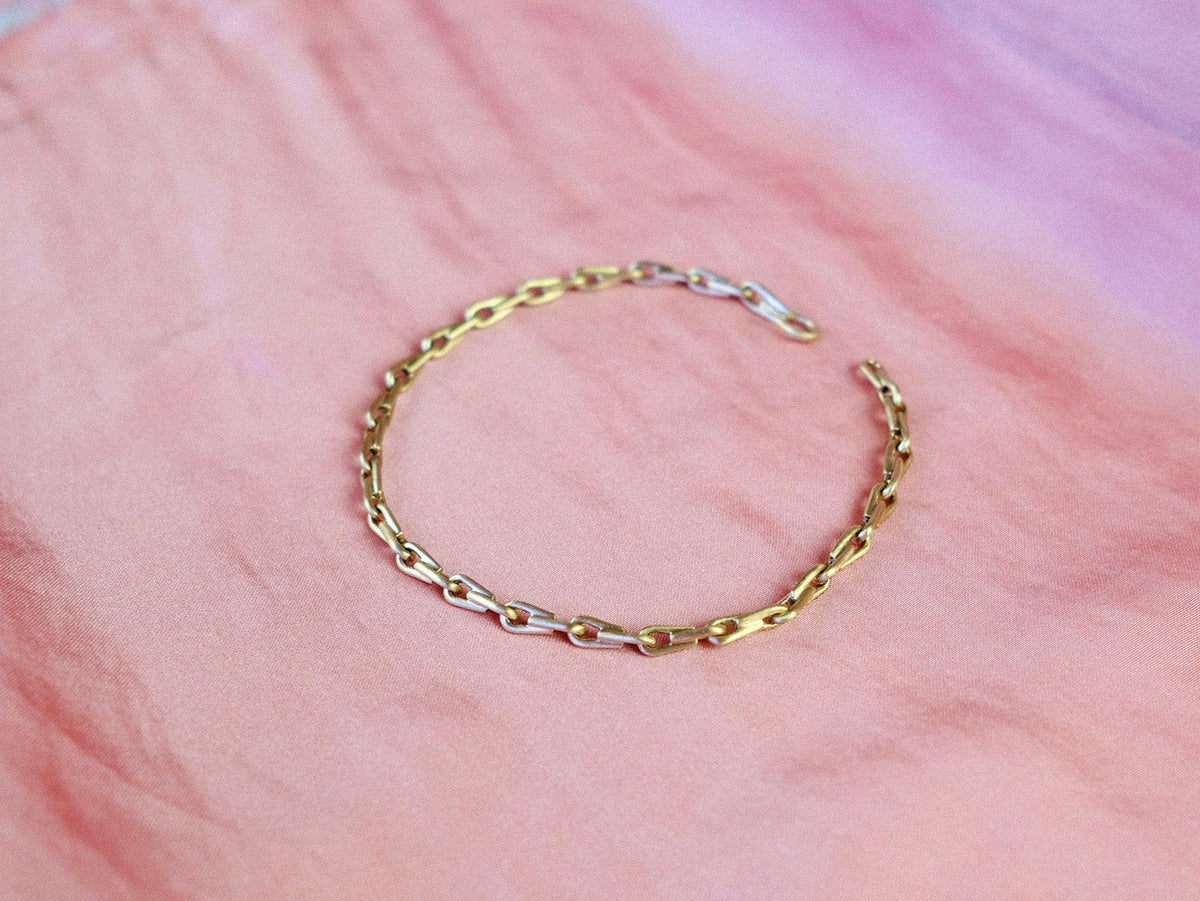 Gold chain bracelet on a pink fabric background
