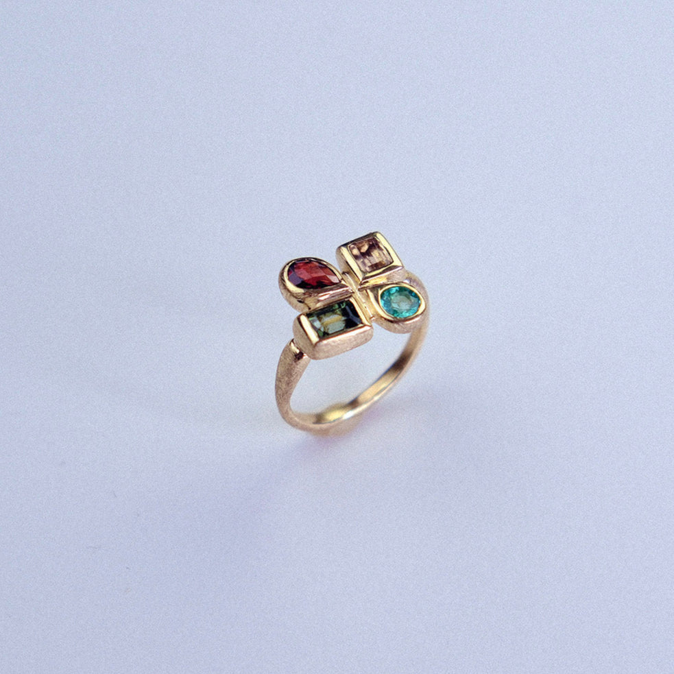 Gold ring with colored gemstones on a light gray background