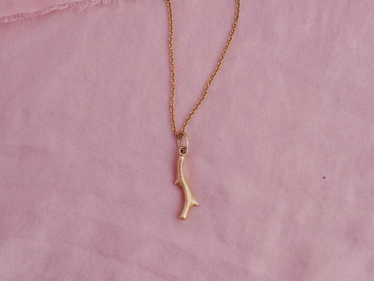 Organic cast coral branch pendant in 18kt gold on pink silk.