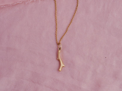 Organic cast coral branch pendant in 18kt gold on pink silk.