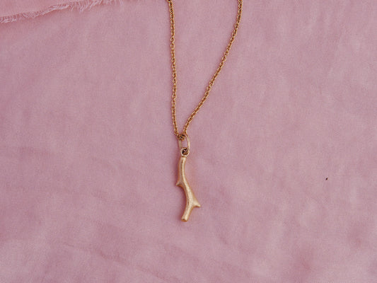 Organic cast coral branch pendant in 18kt gold on pink silk.
