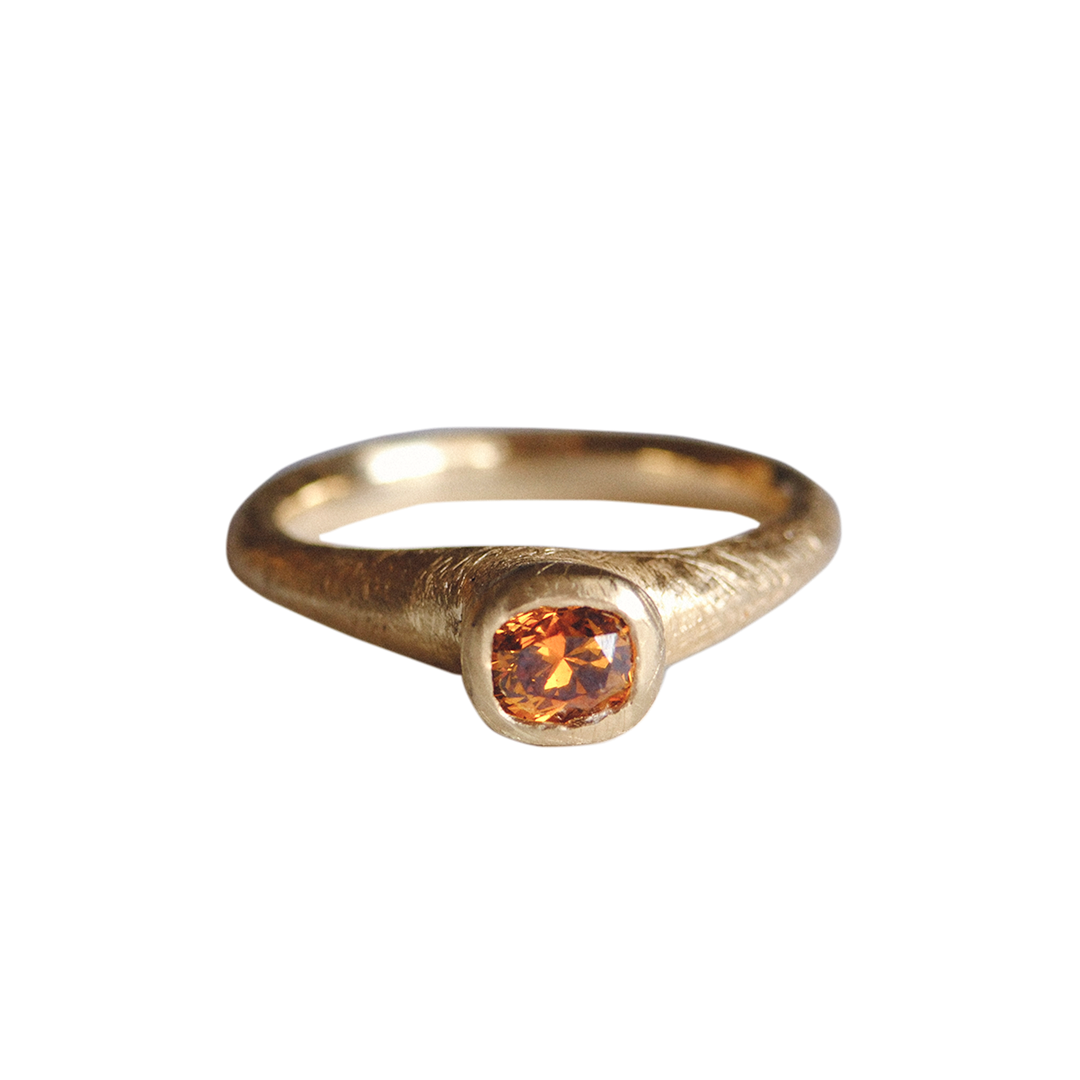 Gold ring with a round orange gemstone on a white background