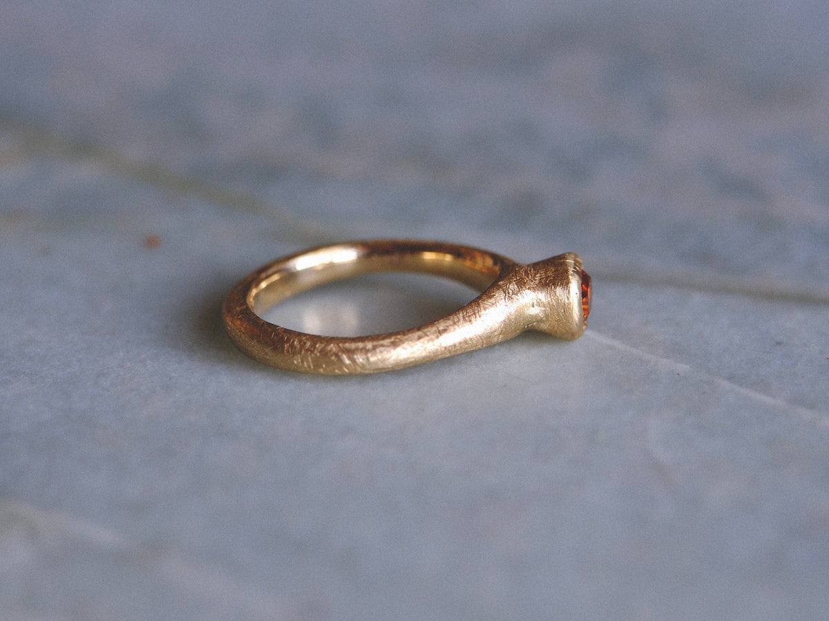 Gold ring with a cognac diamond on a textured gray background