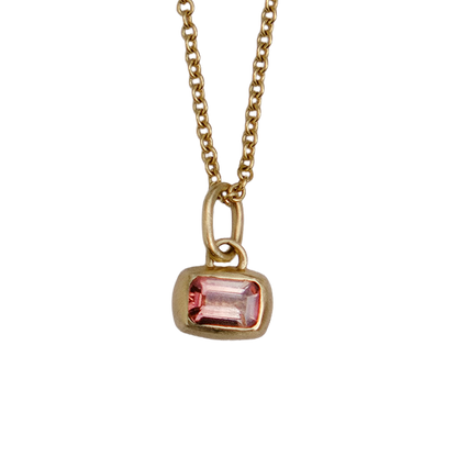 A gold chain necklace with a small rectangular pink gemstone pendant, shown against a plain white background.