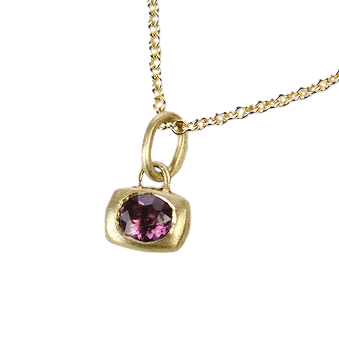 Gold necklace with a purple gemstone pendant on a white background