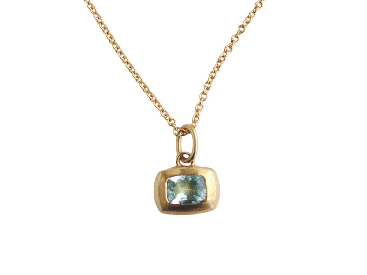 Gold necklace with a pendant featuring a blue gemstone on a white background