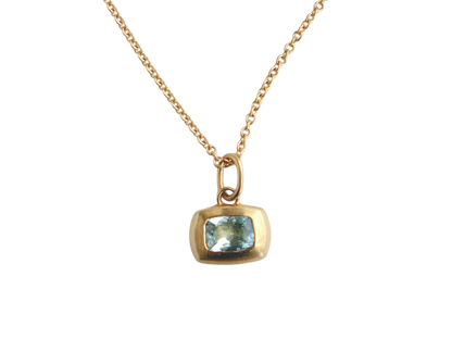 Gold necklace with a pendant featuring a blue gemstone on a white background