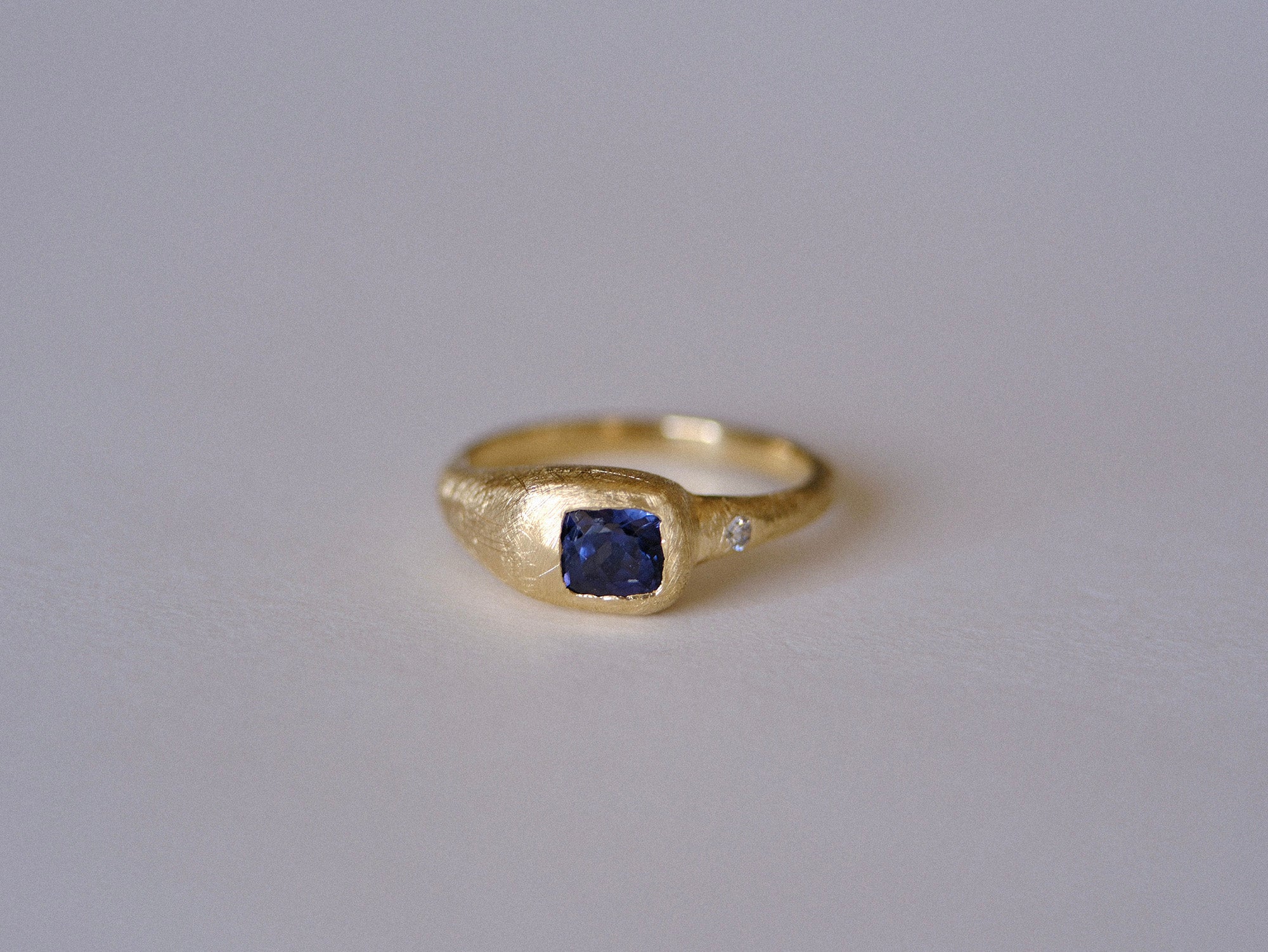 Gold ring with a blue gemstone on a gray background