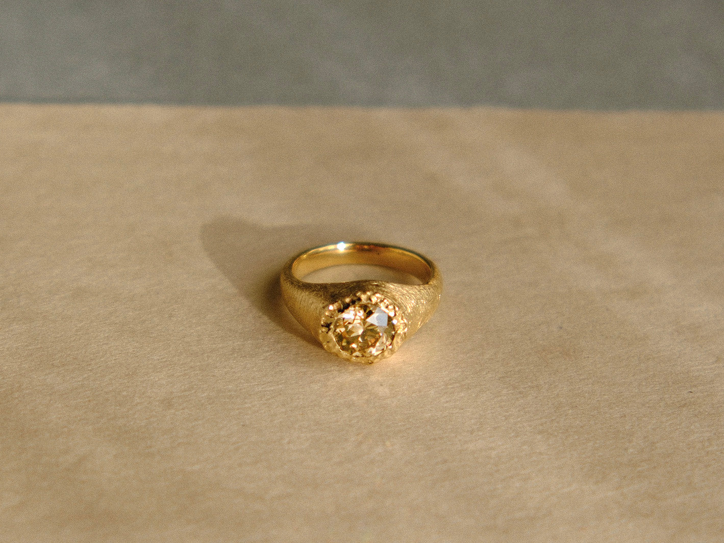 Gold ring with a textured design on a beige surface