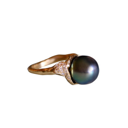 Organic gold ring with a large black pearl and small white diamonds on a white background