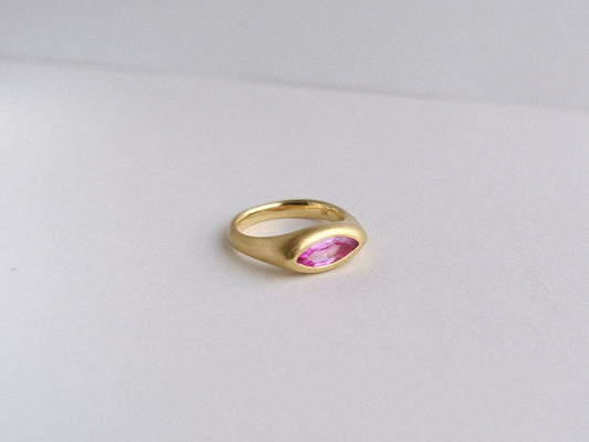 Gold ring with a pink gemstone on a light gray background