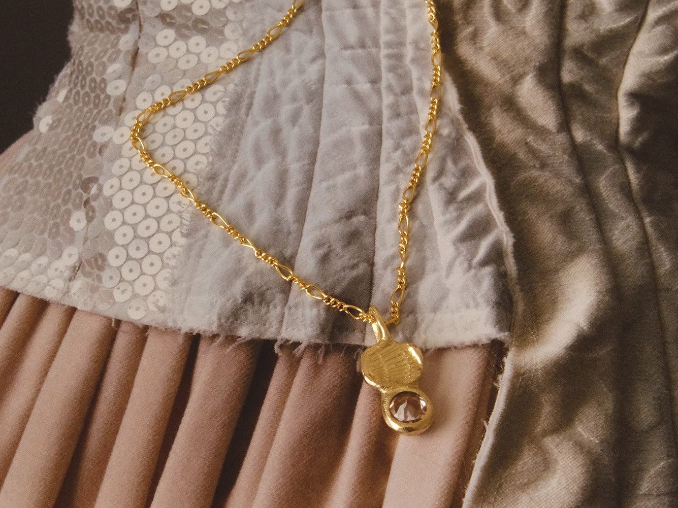 Gold necklace with a pendant on a textured fabric background