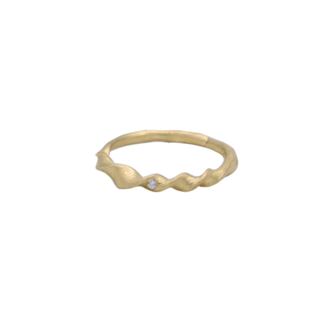 Organic twisted gold ring with a small gemstone on a white background
