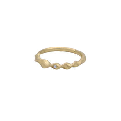 Organic twisted gold ring with a small gemstone on a white background